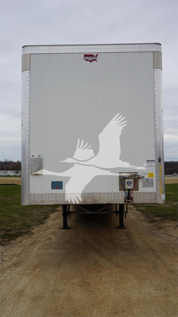 Rear view of a Wabash Duraplate trailer with white bird graphic, van trailer undercarriage and external power connection visible.