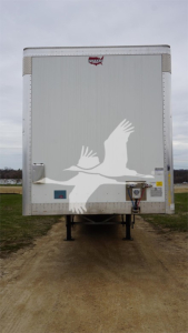 Rear view of a Wabash Duraplate trailer with white bird graphic, van trailer undercarriage and external power connection visible.