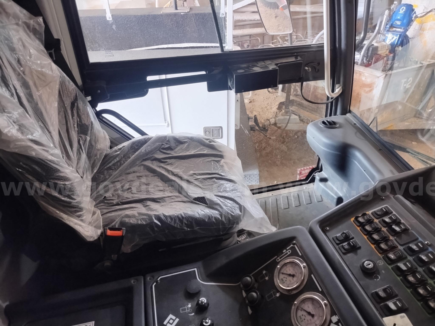 Cab interior of a used Elgin 6000 sweeper showing driver's seat with plastic cover and instrument cluster with gauges and controls.