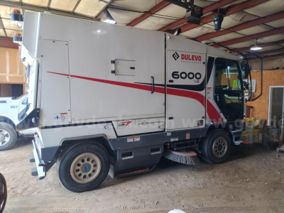 Side view of a white Elgin 6000 sweeper truck with red diagonal graphic and Dulvo branding, showing 6000 emblems and a side access door.
