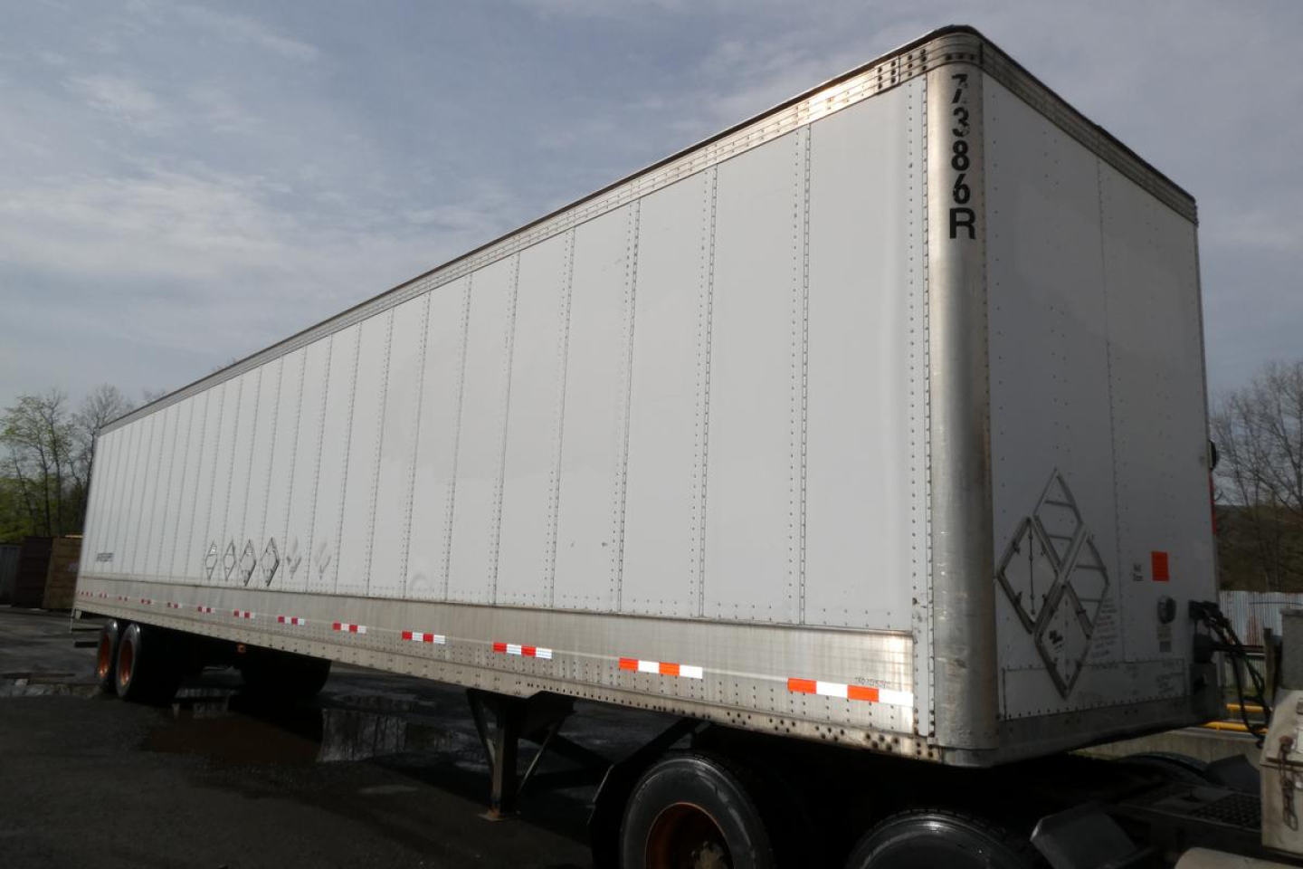 Trailer rear and side view of a long silver Vanguard VXP trailer with tandem axles and reflective safety tape.