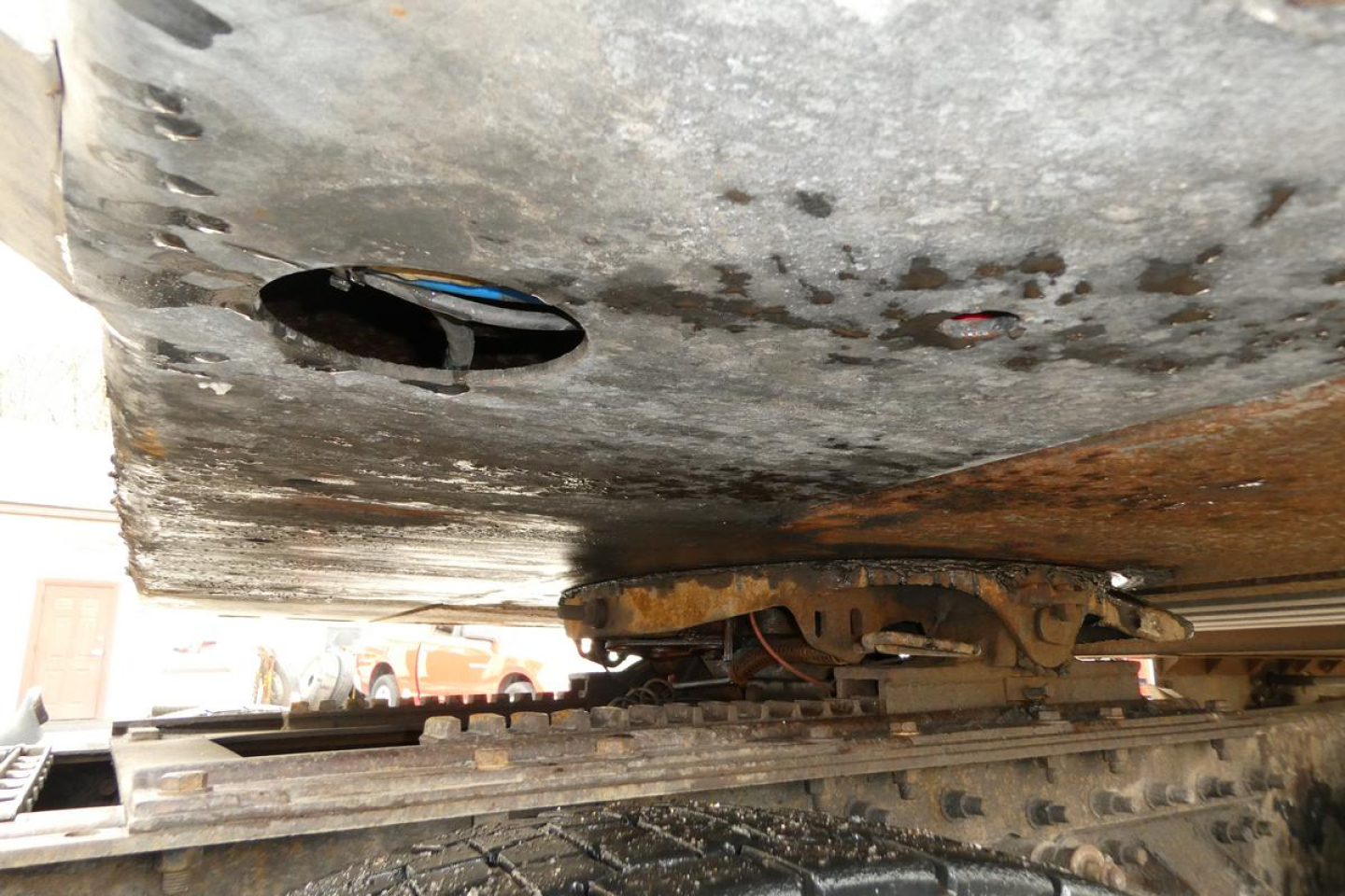 Underbelly of Vanguard trailer showing steel frame and hitch assembly, rusty components and exposed underside.