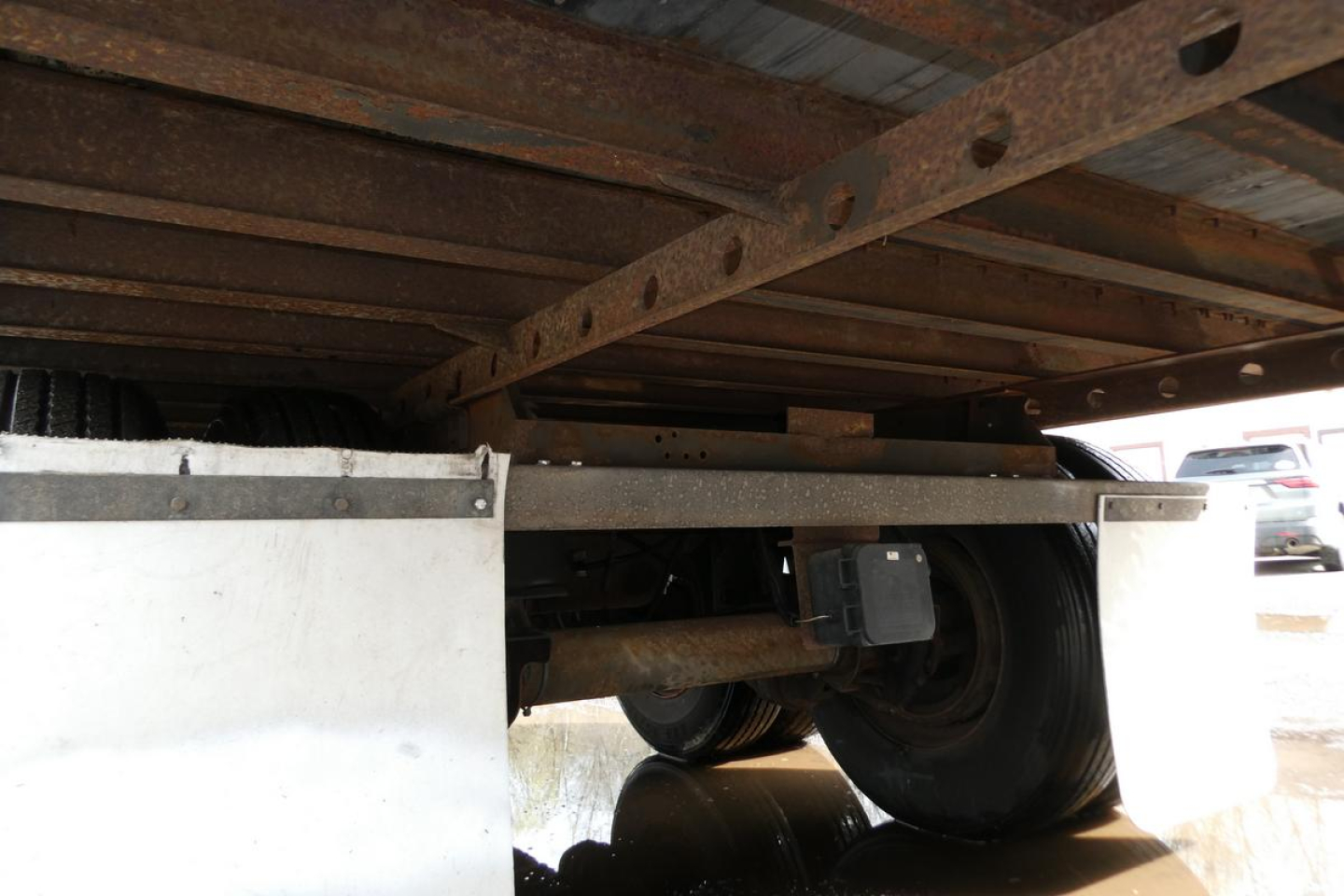 Trailer undercarriage showing dual rear wheels, leaf spring suspension, and chassis rails beneath a Vanguard VXP trailer.