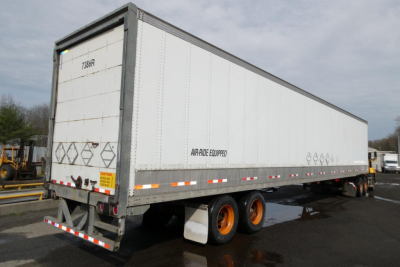 Vanguard VXP trailer showing white exterior with orange dual rear wheels and reflective safety stripes along lower edge.