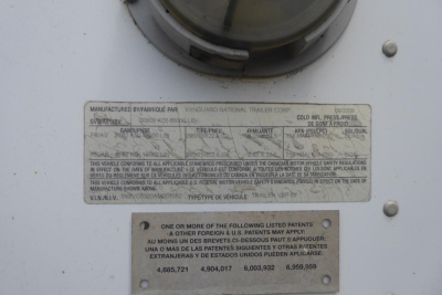 Van trailer side plate showing manufacturer and weight/safety labels with VIN 5V8VC5320AM001082 and Canadian motor vehicle safety standards text.