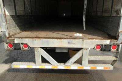 Rear of Vanguard VXP trailer showing open cargo area, rear bumper with lights, and a ramp-like frame. There is stamped or etched text on the frame: 'ROY...?' and a few small labels.