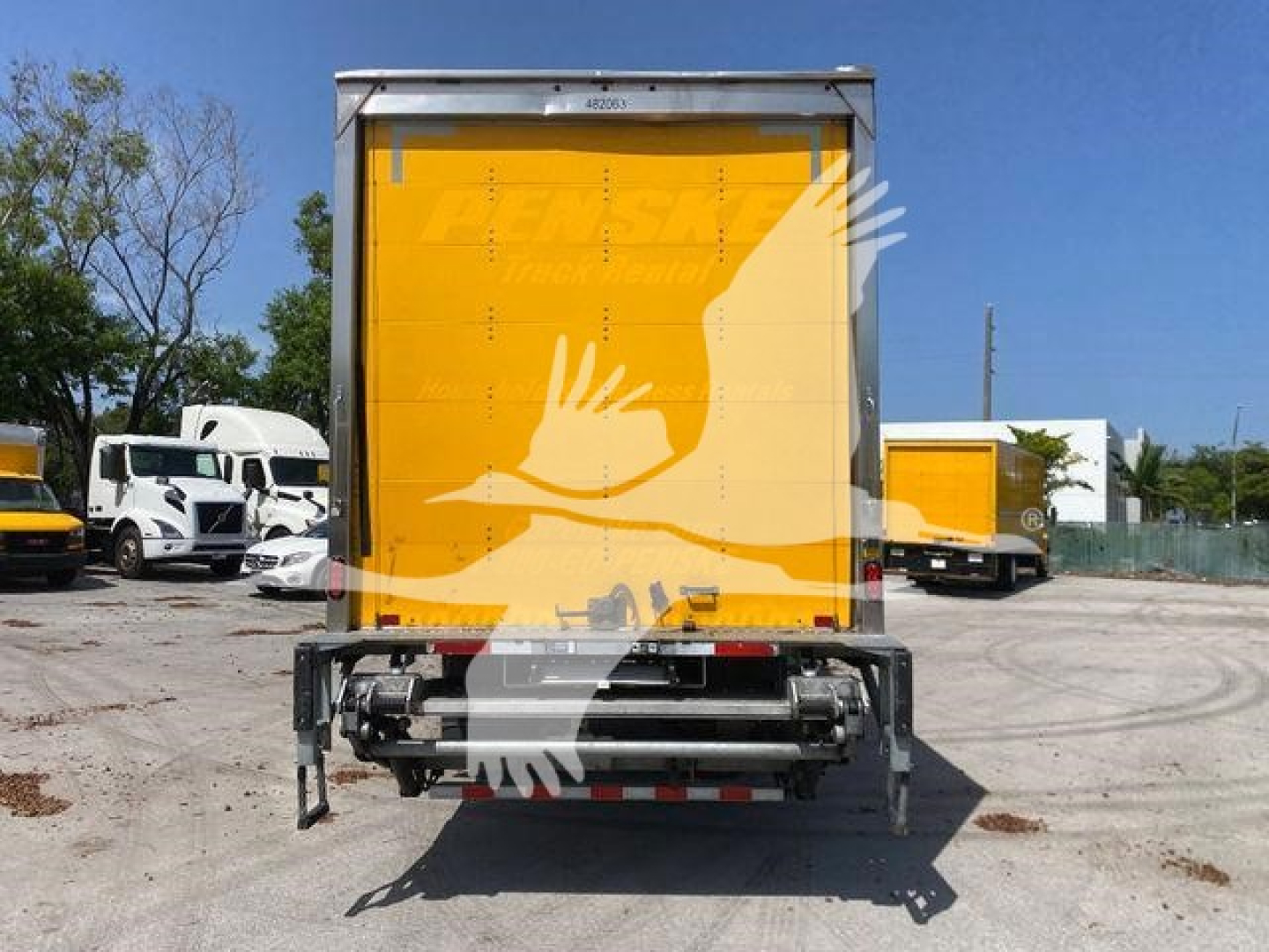 Box truck rear showing yellow cargo door and hydraulic lift undercarriage with bumper guards.