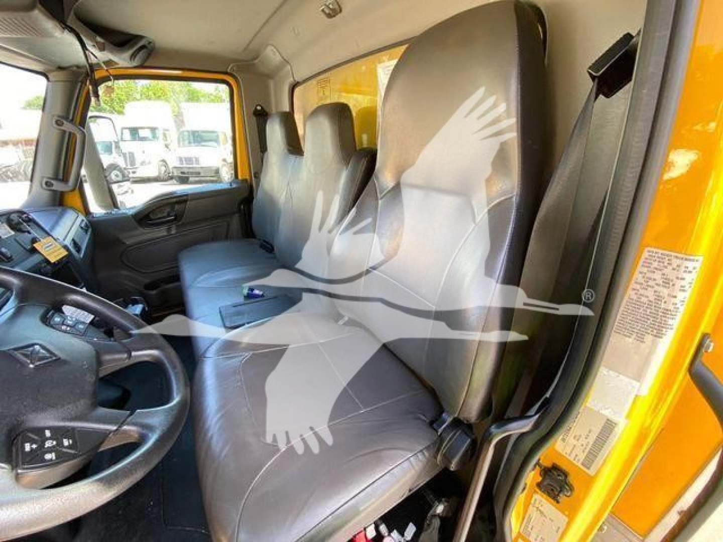 Cab interior of a 2022 International MV truck showing front seats, steering wheel, door frame, and yellow exterior frame.