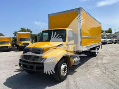 Box truck with yellow cab and yellow box, VIN 3HAEUMML5NL381694 visible; stock number T81694; International MV medium-duty box truck; front grille and headlights visible; other trucks in background.
