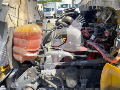 Engine bay of a 2022 International MV truck showing coolant reservoir, hoses, and various engine components.