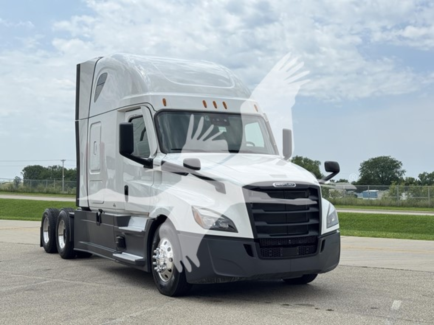 Truck cab front and side view showing Freightliner Cascadia 126 sleeper with white and black color scheme, dual rear axles, highway setting.