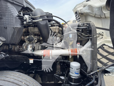 Freightliner Cascadia engine bay showing Suzuki? actually clear: diesel engine with intake piping, coolant reservoir, and filter canister in view.