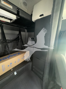 Freightliner Cascadia cab interior showing bunk area with storage shelf and cardboard box.