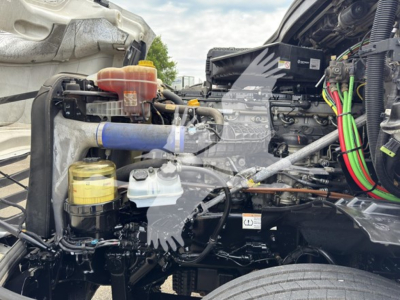 Cascadia engine bay showing coolant reservoir, yellow cap, blue hose, air intake, and various wiring in a Freightliner truck.
