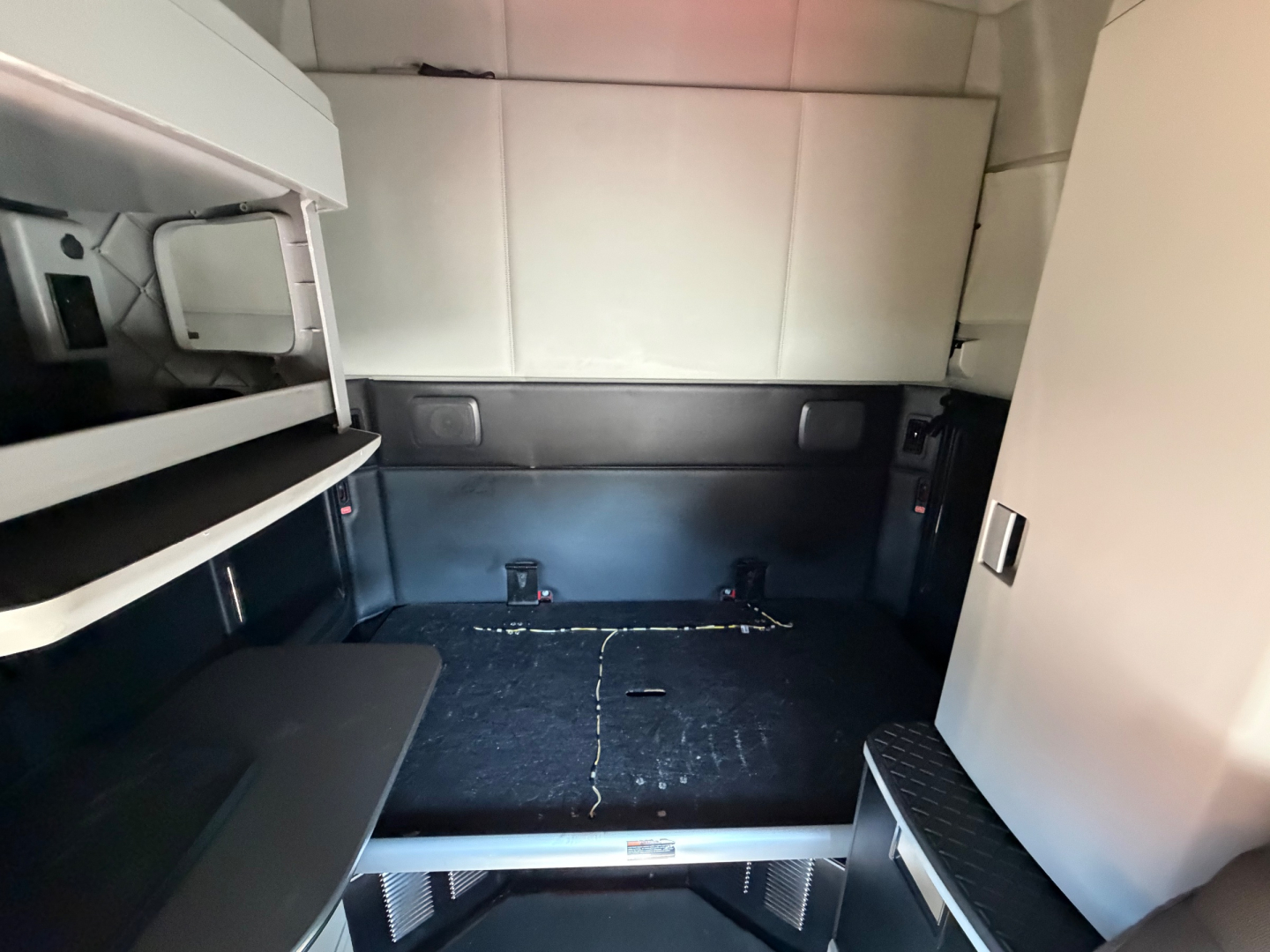 Kenworth truck sleeper cab interior showing rear storage area and steps; no legible text visible on image