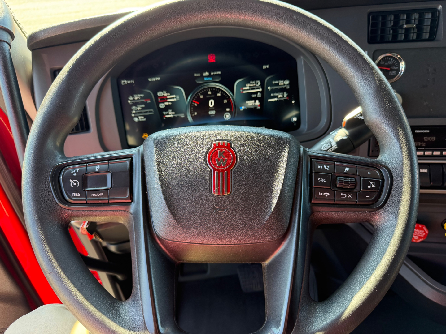 Kenworth T680 steering wheel and dashboard view with instrument cluster, center console controls, and Kenworth emblem visible.