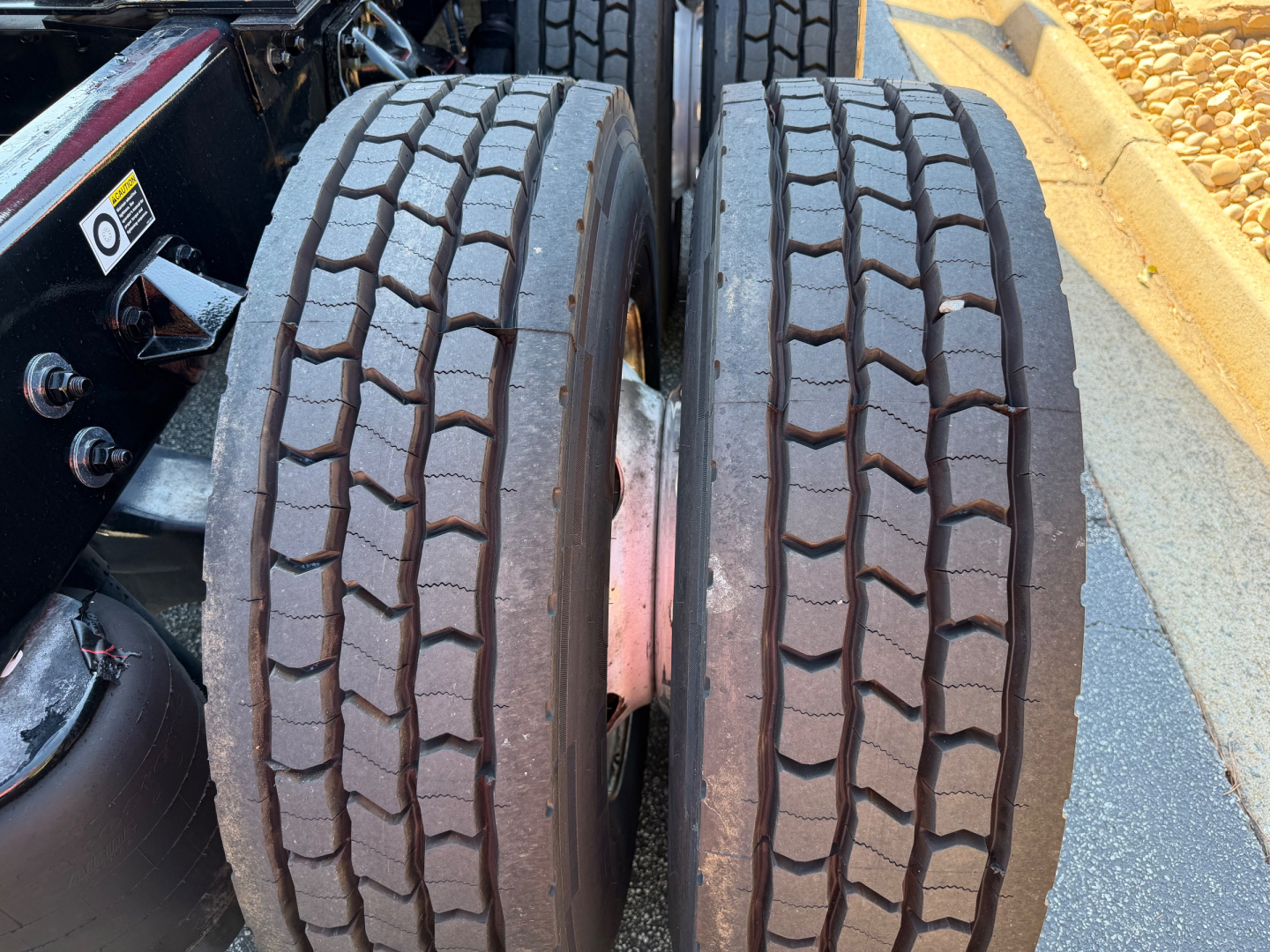 Twin rear tires of a Kenworth truck showing tread pattern and wheel assembly in-view.