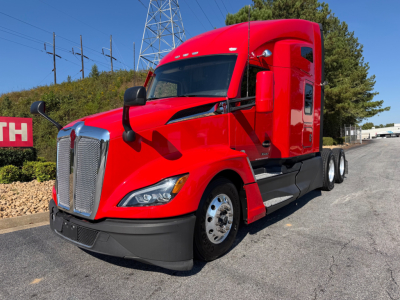 Kenworth T680 conventional sleeper tractor in red, front-left view, showing large chrome grille, dual front wheels, side mirrors, and sleeper cab.