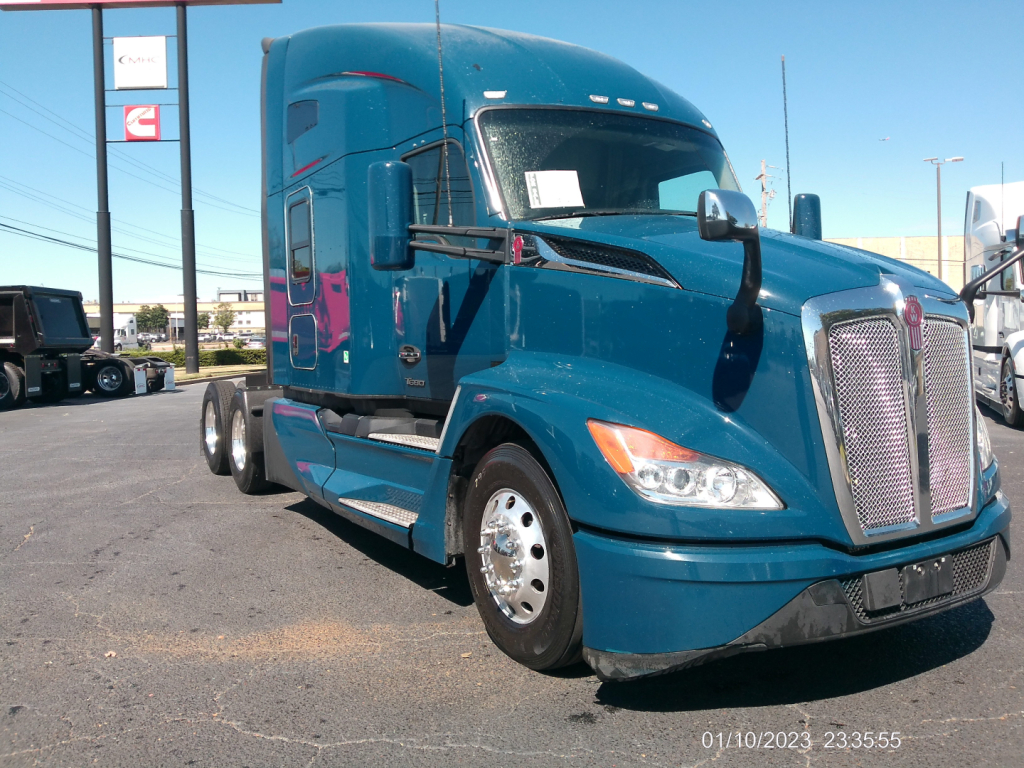 Kenworth T680 sleeper cab tractor in blue showing front grille and passenger side with wheel and side mirror.