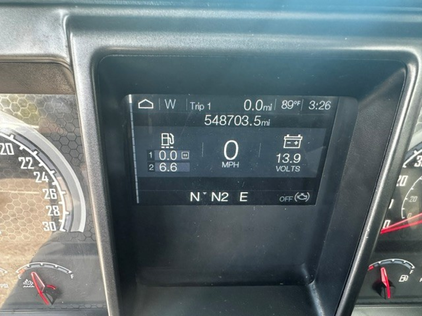 Digital instrument cluster showing Trip 1 0.0 mi, 0 MPH, 899°F? 3:26, 13.9 volts, 548703.5 miles, N N2 E, with fuel and RPM gauges around.