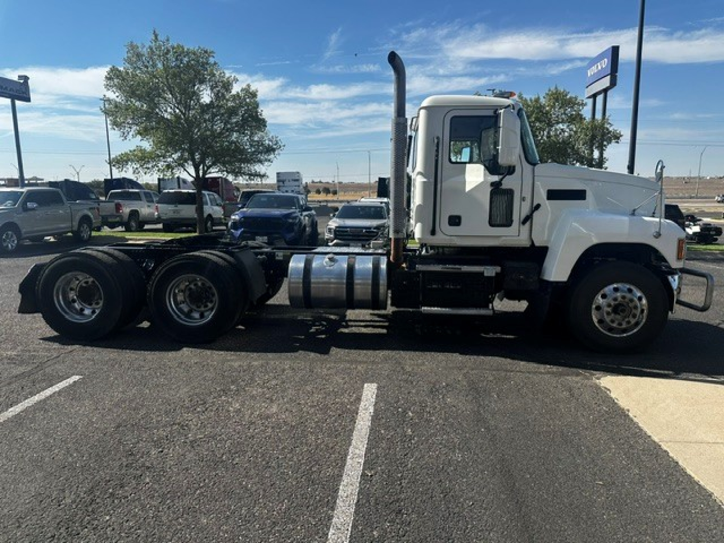 Truck chassis side view showing cab with exhaust stack, fuel tanks, and rear axles of a 2020 Mack PI64T conventional daycab.