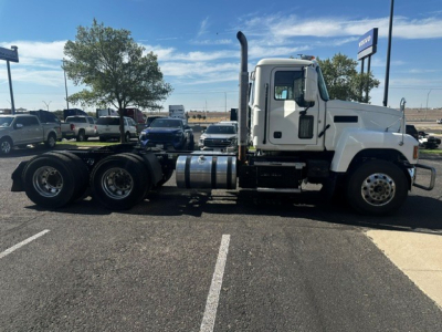 Truck chassis side view showing cab with exhaust stack, fuel tanks, and rear axles of a 2020 Mack PI64T conventional daycab.