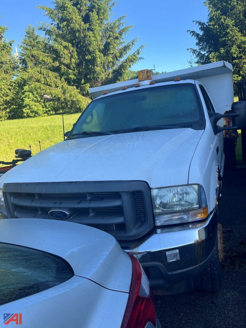 Ford F-450 dump truck in-service shown from front-right angle with amber beacon lights and dump body visible.