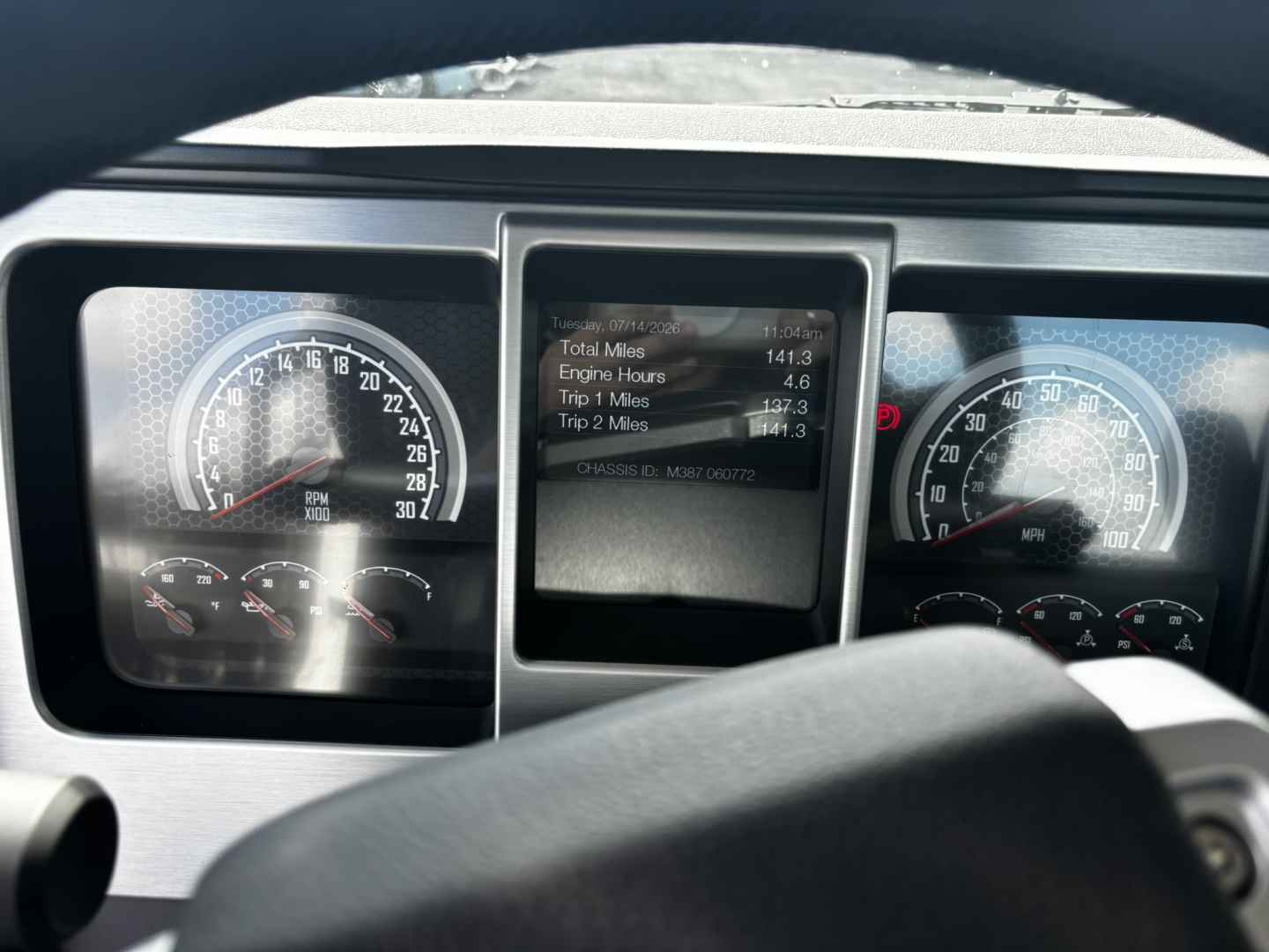 Dashboard and instrument cluster of a 2027 Mack GR64FT showing gauges and a central digital display with vehicle data. Readouts visible include engine hours and trip data, with the steering wheel in foreground.