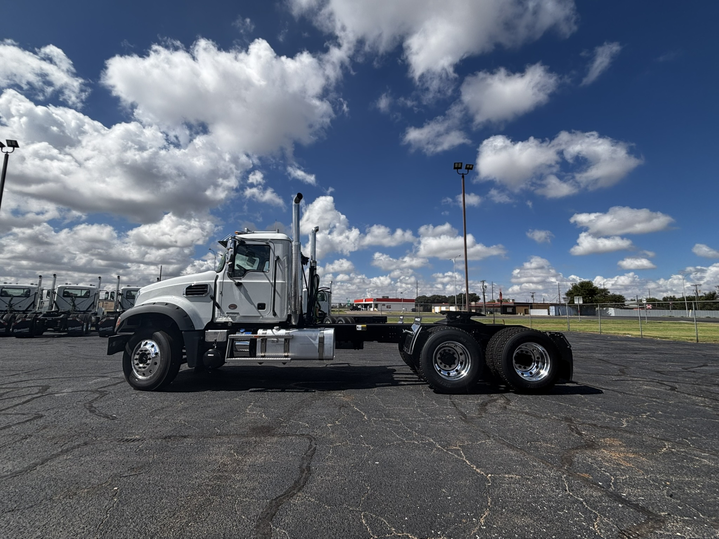 2027 Mack GR64FT conventional daycab truck side view showing cab, dual rear axles, chrome exhaust stacks, and white exterior.