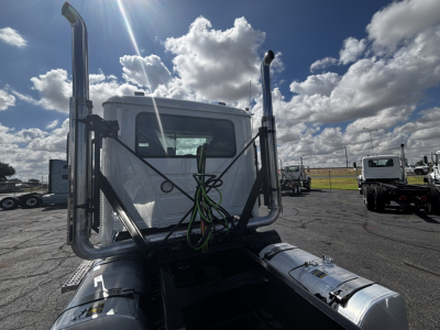 Front view of a 2027 Mack GR64FT sleeper or day cab chassis with dual vertical exhaust stacks and green wiring harness.