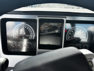Dashboard and instrument cluster of a 2027 Mack GR64FT showing gauges and a central digital display with vehicle data. Readouts visible include engine hours and trip data, with the steering wheel in foreground.