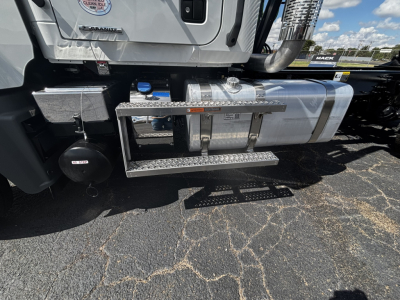 Truck side view showing fuel tank and chrome steps on a Mack GR64FT cab over-engine with metal steps and hydraulic lines.