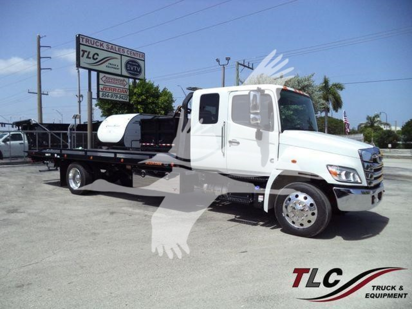Front right side view of a white 2026 Hino L6 rollback tow truck with flatbed, cab doors, and large mirrors.