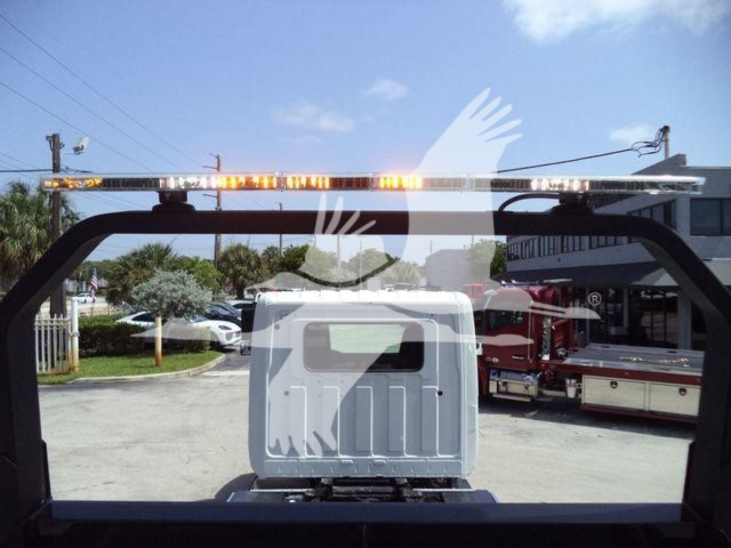 Back view of a 2026 Hino L6 rollback truck showing rear cab window and a rooftop warning light bar.