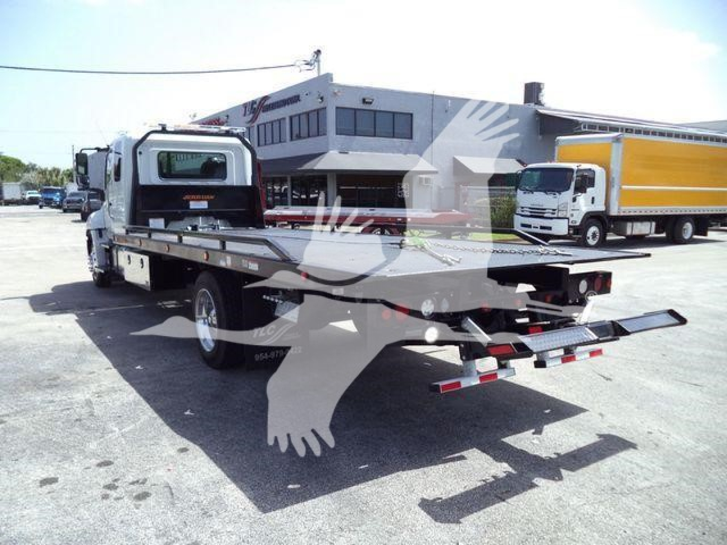 Truck bed with rollback tow truck showing flatbed and rear ramps.