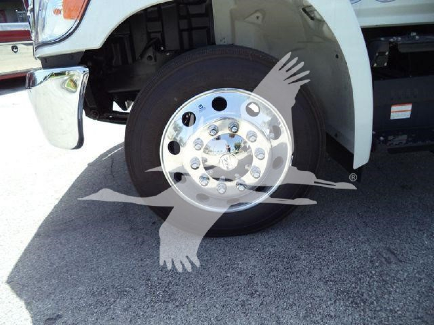 Front wheel of a 2026 Hino L6 rollback truck showing wheel hub and fender; watermark of a bird logo across image.