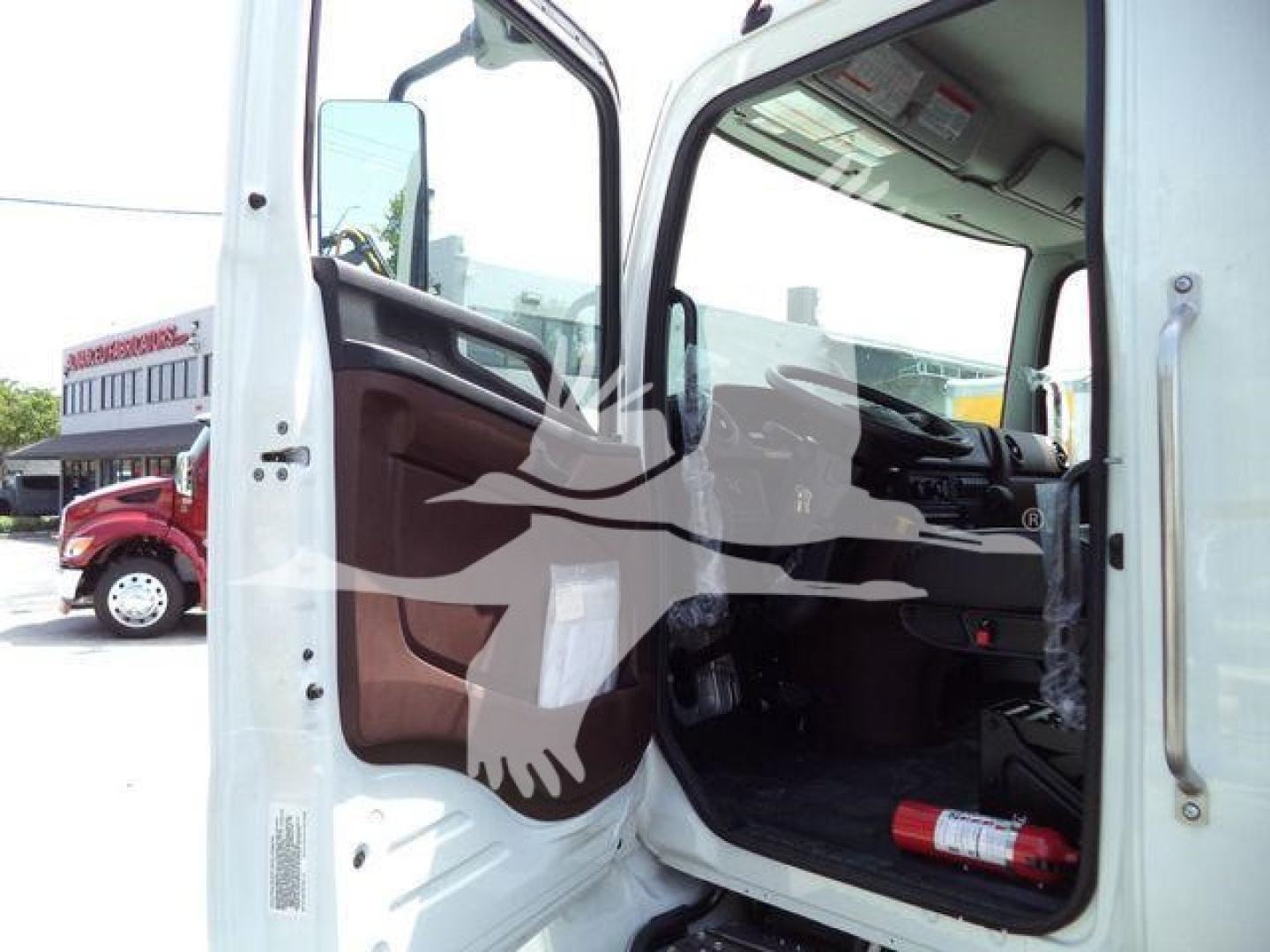 Truck cab interior view from open driver door showing steering wheel dashboard and seating.