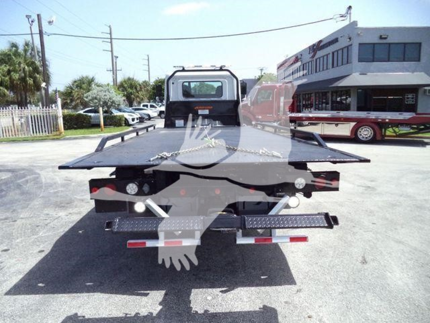 Flatbed tow truck bed rear view showing hydraulic ramps and rear lights.