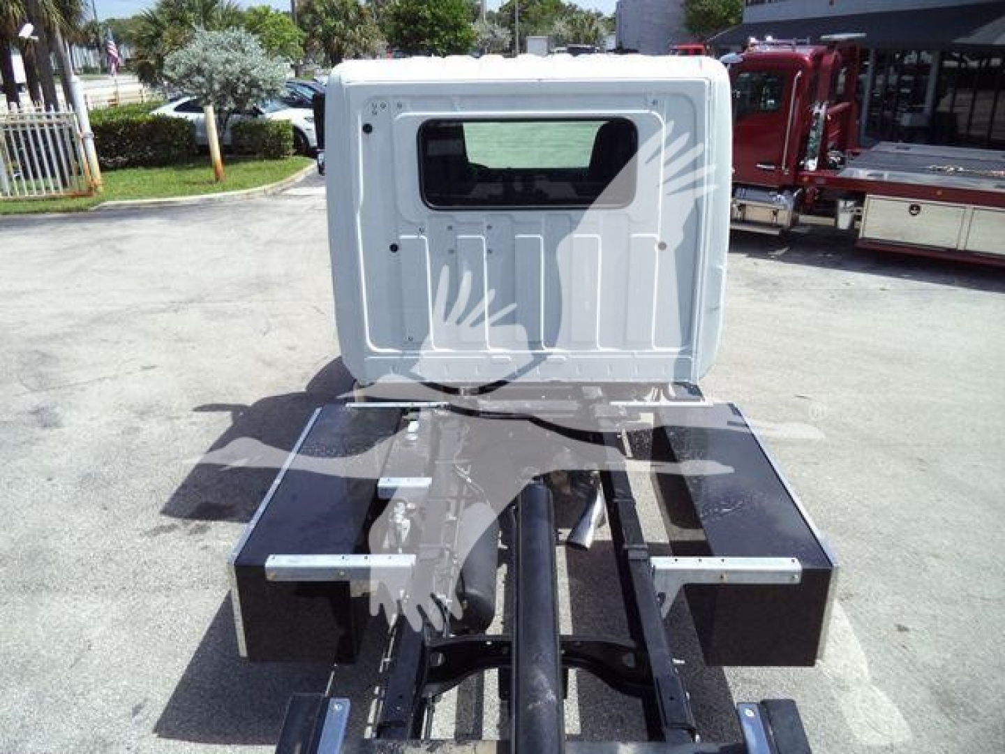 Truck cab rear view showing chassis and mounting frame for rollback truck with black metal toolbox boxes and white cab roof.