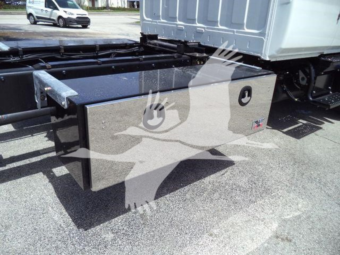 Roll-back truck undercarriage showing a rectangular aluminum toolbox mounted between frame rails.