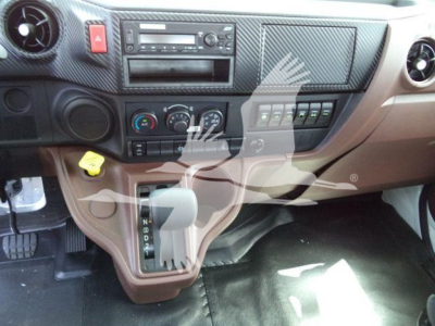 Dashboard view of a 2026 Hino L6 cab interior showing gear selector, climate controls, radio, and brown dash. Visible text includes on/off symbols and control labels.