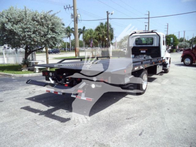 Flatbed rollback tow truck with a rear ramp and hydraulic platform, cab at front, chain hooks, and taillights visible.