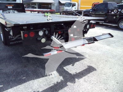 Flatbed tow truck trailer with rear deck and access steps; visible hydraulics, lights, and bumper. 2026 Hino L6 listing image with platform and tail section in lot.