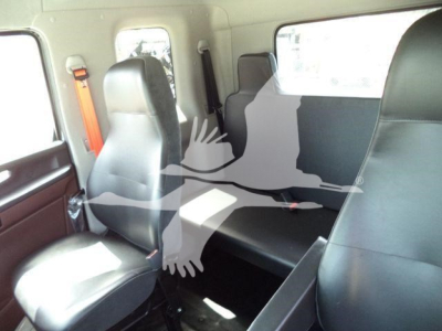 Interior of 2026 Hino L6 rollback truck showing seating area and cabin; black vinyl seats, seat belts, window, and partial view of rear area.