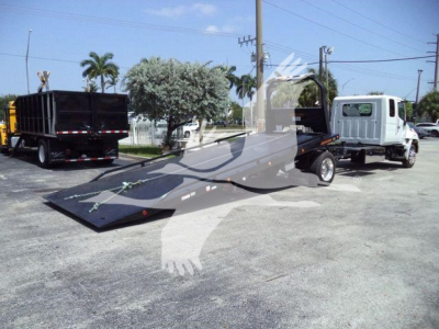 Truck with flatbed rollback equipment showing Hino L6 engine bay components and platform attachment.
