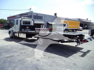 Hino L6 rollback truck showing flatbed with tow hitch and rear equipment.