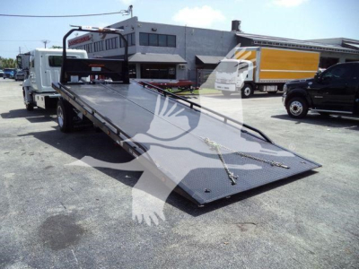 Hino L6 rollback truck with a lowered flatbed ramp in an outdoor lot