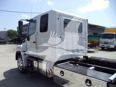 Hino L6 truck cab visible from left-rear angle showing side window, door, and chassis frame; no visible logos or text legible.