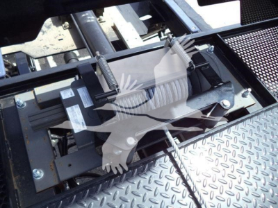 Truck bed entry showing hydraulic winch motor and roller fairlead assembly with spring-loaded mechanism and textured diamond plate surface.