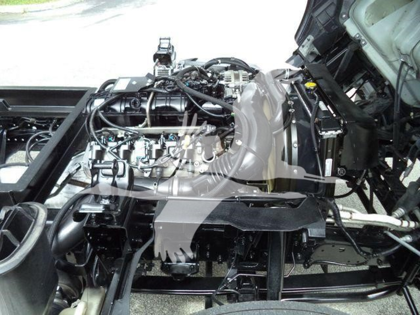 Front engine bay of a 2017 Chevrolet W4500 dump truck showing engine components, wiring, and chassis frame.